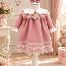 O rochiță de botez elegantă pentru fetiță, realizată într-o nuanță delicată de roz pudrat, completată de detalii ivoire și dantelă fină. Modelul se remarcă prin gulerul amplu ivoire, decorat cu dantelă și un detaliu tip bijuterie în partea centrală. Mânecile lungi sunt completate de manșete ivoire cu volănașe, păstrând aspectul delicat și armonios al ținutei. Partea inferioară a rochiței este decorată cu broderie florală și dantelă ivoire, care oferă modelului un aspect elegant și festiv. Croiala lejeră și fusta amplă completează stilul clasic al rochiței. Ținuta este însoțită de accesoriul pentru cap cu fundă roz asortată, pentru un look complet. Potrivită pentru botez, ceremonia religioasă, aniversări, petreceri și ședințe foto. Setul include: rochiță + accesoriu pentru cap asortat.