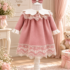 O rochiță de botez elegantă pentru fetiță, realizată într-o nuanță delicată de roz pudrat, completată de detalii ivoire și dantelă fină. Modelul se remarcă prin gulerul amplu ivoire, decorat cu dantelă și un detaliu tip bijuterie în partea centrală. Mânecile lungi sunt completate de manșete ivoire cu volănașe, păstrând aspectul delicat și armonios al ținutei. Partea inferioară a rochiței este decorată cu broderie florală și dantelă ivoire, care oferă modelului un aspect elegant și festiv. Croiala lejeră și fusta amplă completează stilul clasic al rochiței. Ținuta este însoțită de accesoriul pentru cap cu fundă roz asortată, pentru un look complet. Potrivită pentru botez, ceremonia religioasă, aniversări, petreceri și ședințe foto. Setul include: rochiță + accesoriu pentru cap asortat.